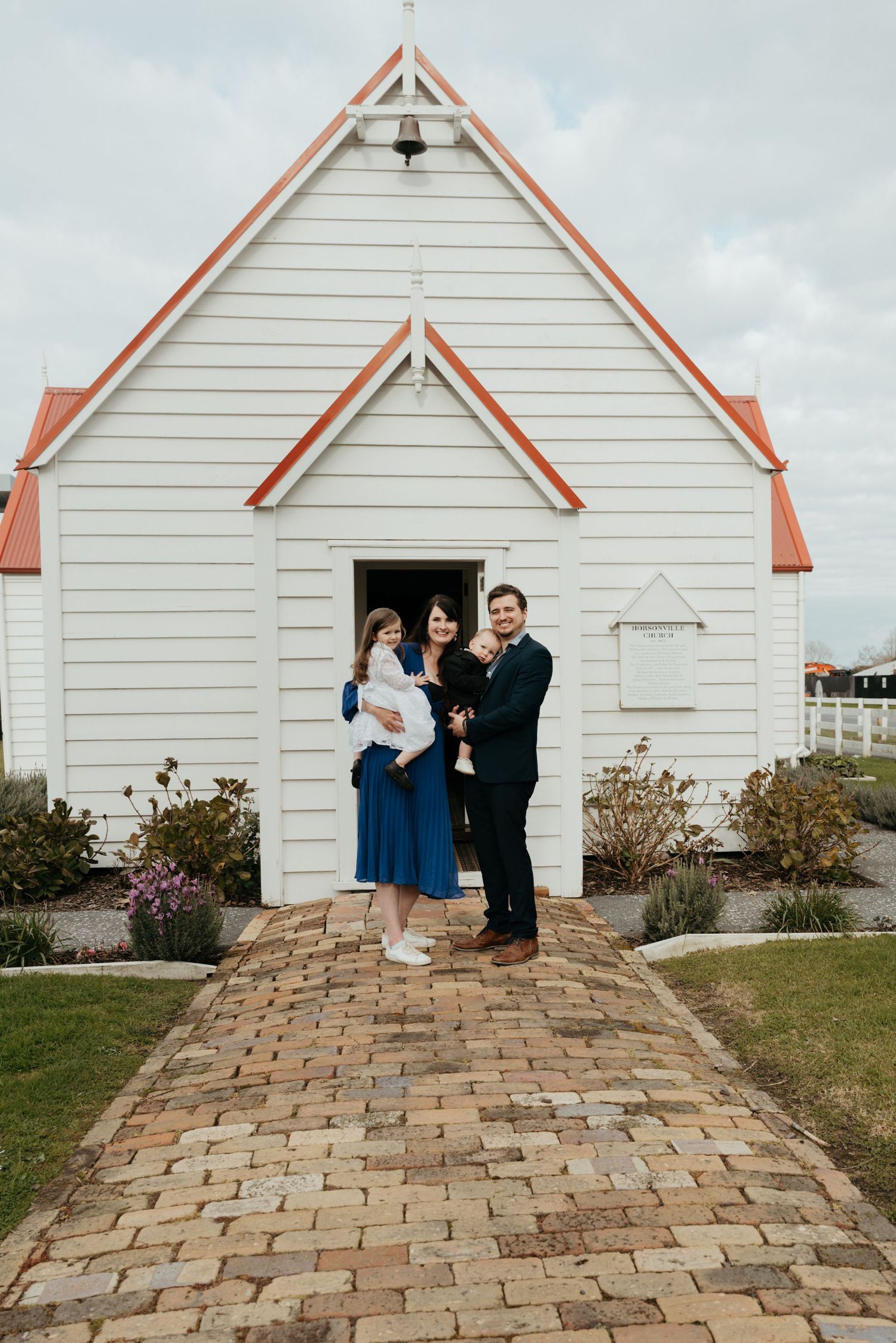 A charming white chapel with orange trim and a brick pathway leading to its entrance.