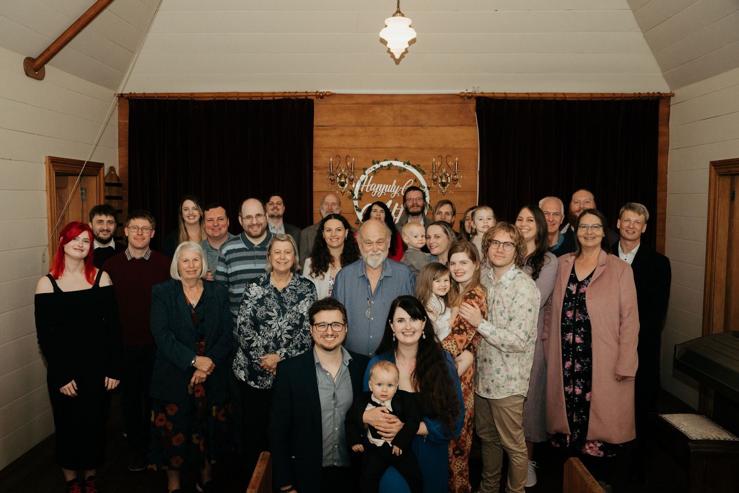 Large group gathered inside a rustic chapel interior for a special occasion.