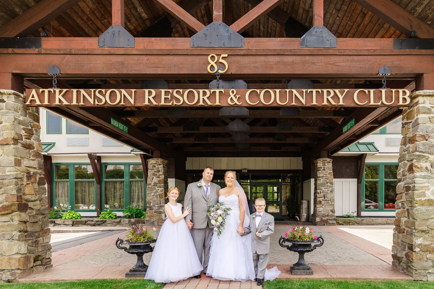 Wedding party standing under the entrance sign of Atkinson Resort & Country Club.