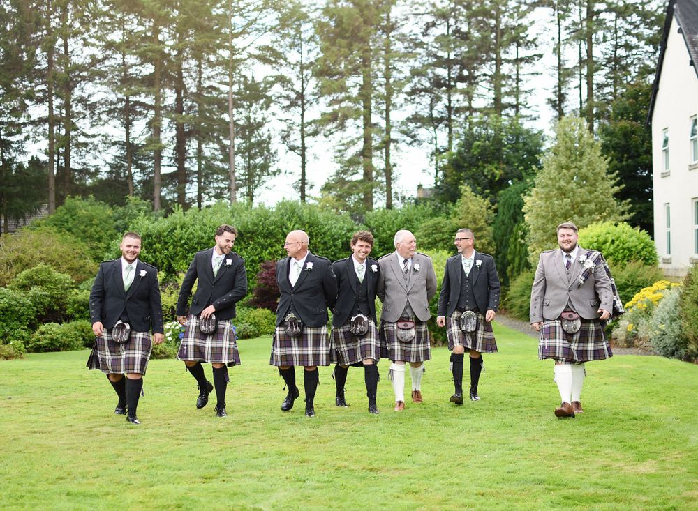 Groom and his grooms men walking through the garden at Balgeddie House Hotel before the wedding ceremony. Looking relaxed and chatting.