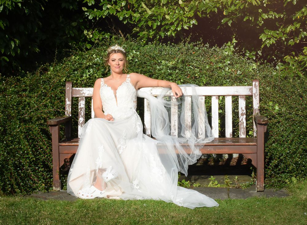 Bride relaxes on a bench in the sun on her wedding day at the double tree Hilton at south Queensferry.