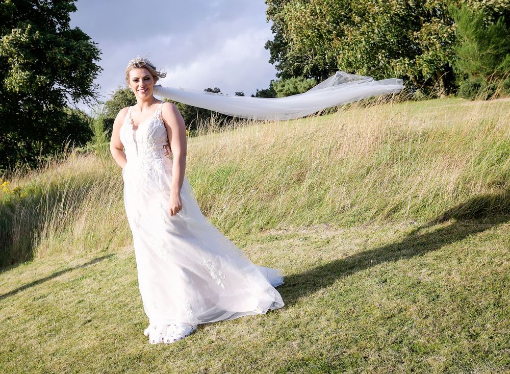 Bride posing on a hill with her veil blowing in the wind at the Double Tree Hilton South Queensferry.