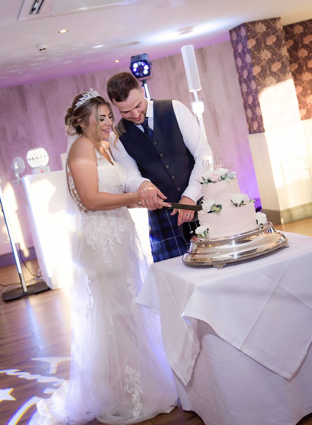 Bride and groom cutting their cake at their wedding reception. Couple looking relaxed and content looking down at the cake.