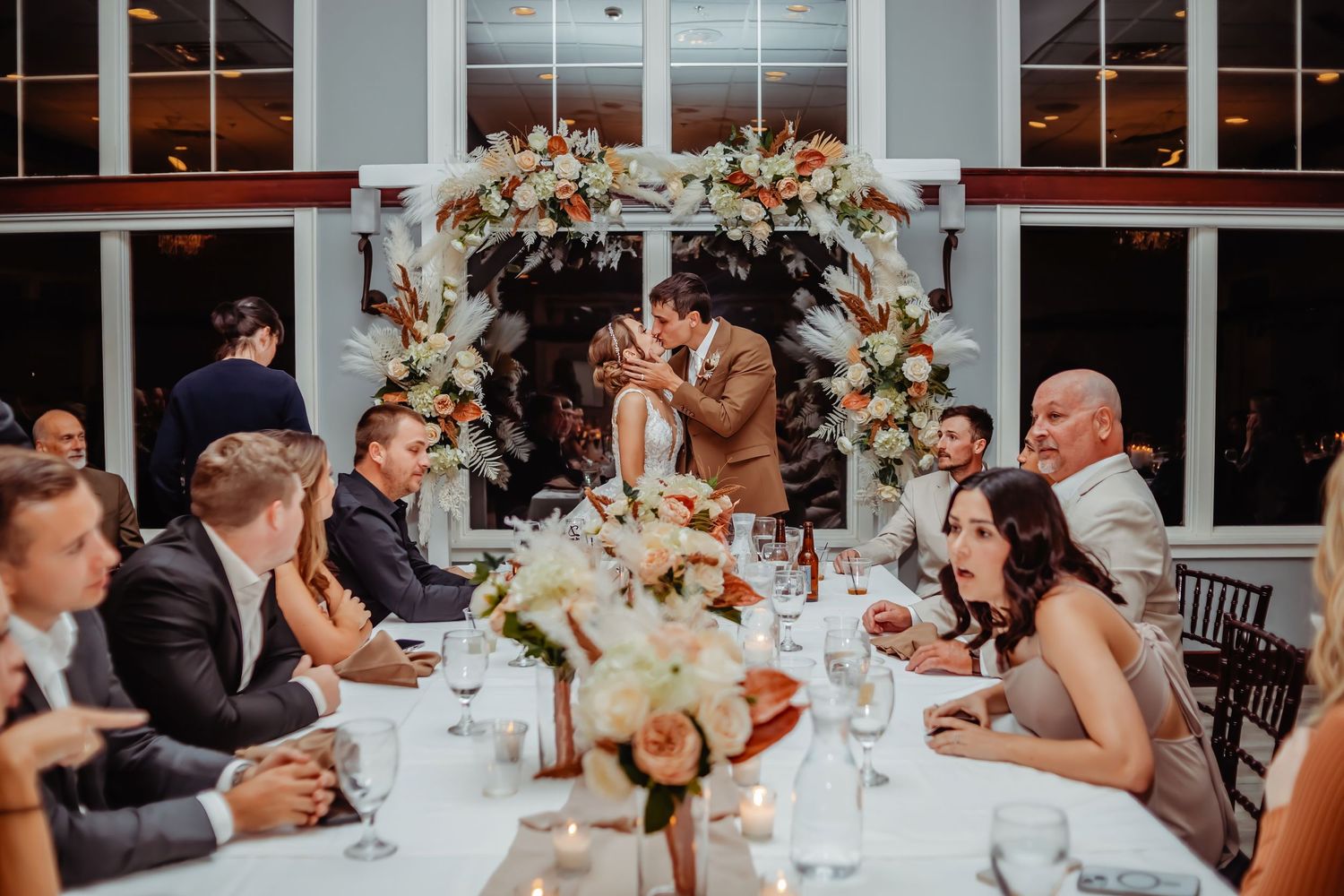 Elegant wedding reception dinner setup with floral arch and intimate table setting for guests.