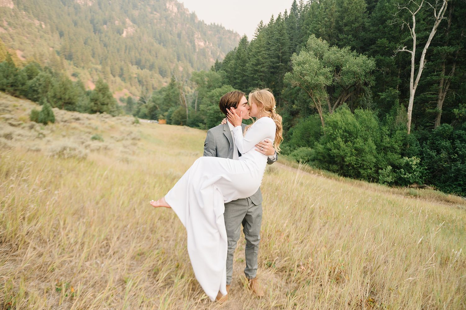 A romantic wedding photo in a mountain meadow with aspen trees and rolling hills.