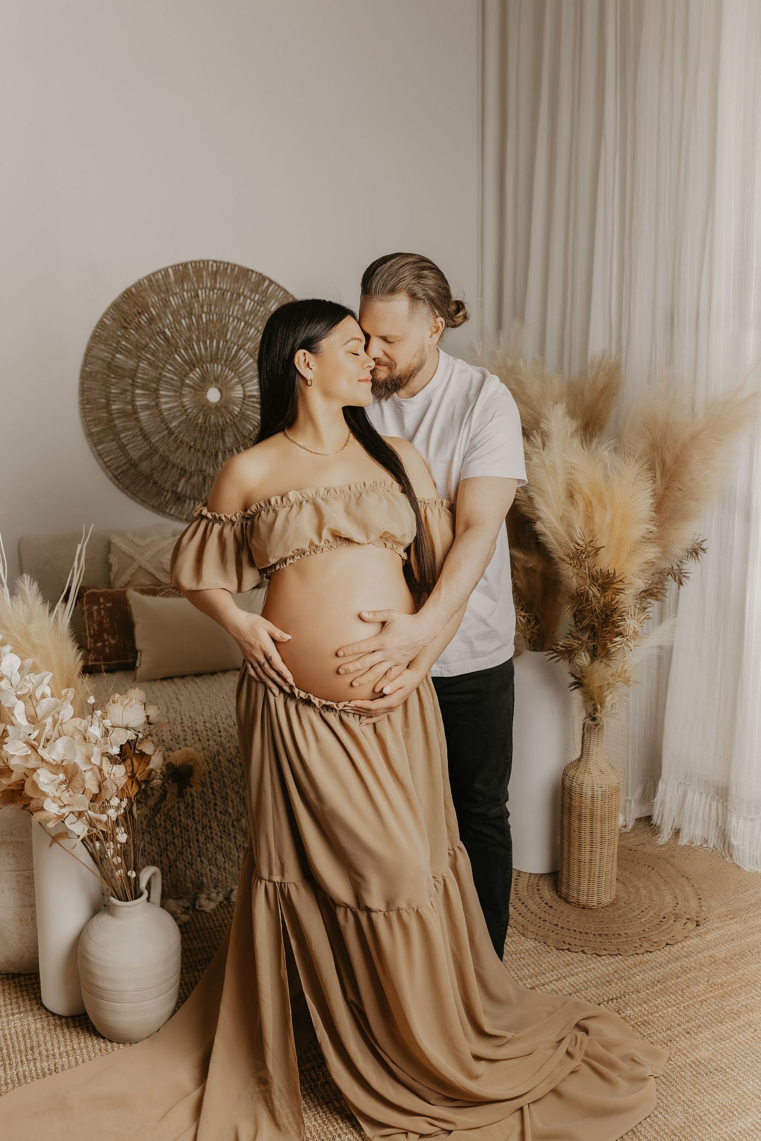 Intimate maternity photos in a neutral-toned room with natural light and decorative wall art.