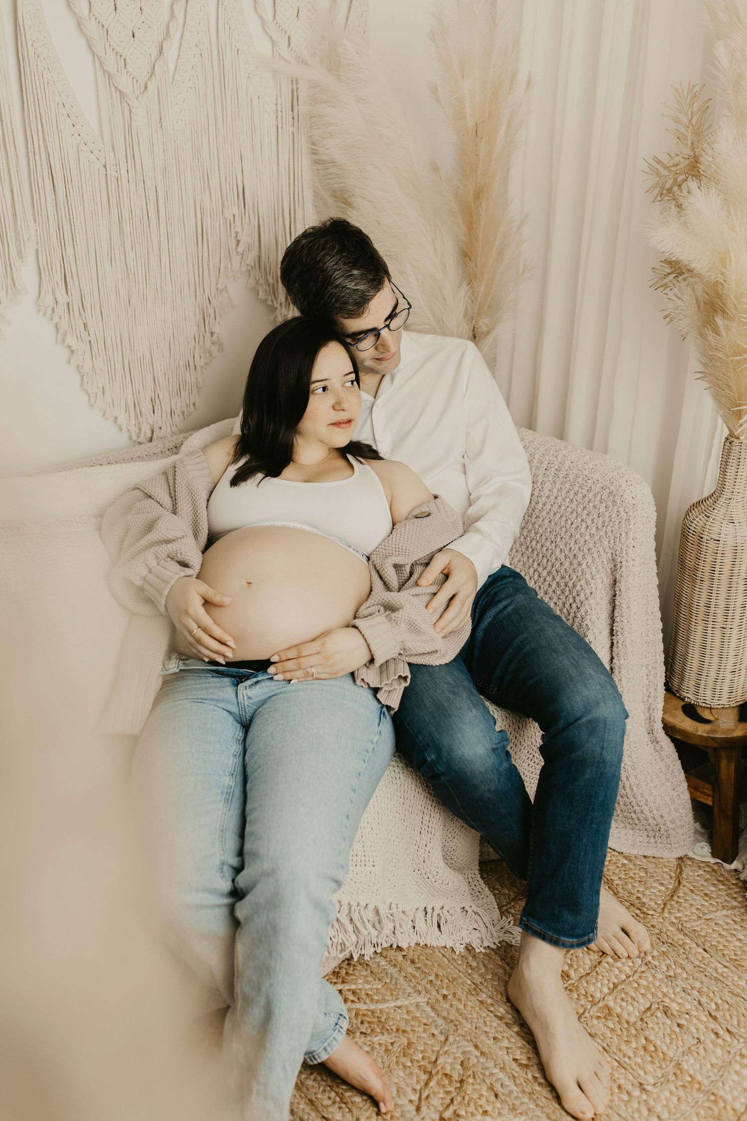Couple sharing tender moments during maternity session on a cozy floor setting.