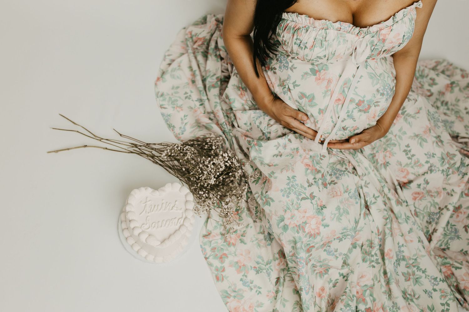 Elegant maternity photo featuring floral dress and natural elements.