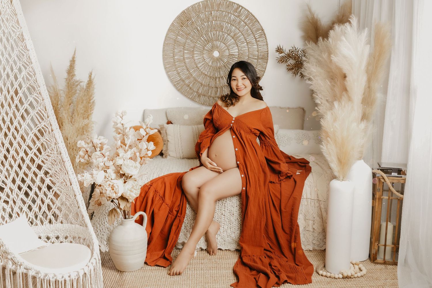 Maternity photography in rust-colored dress with bohemian neutral decor and dried flowers.