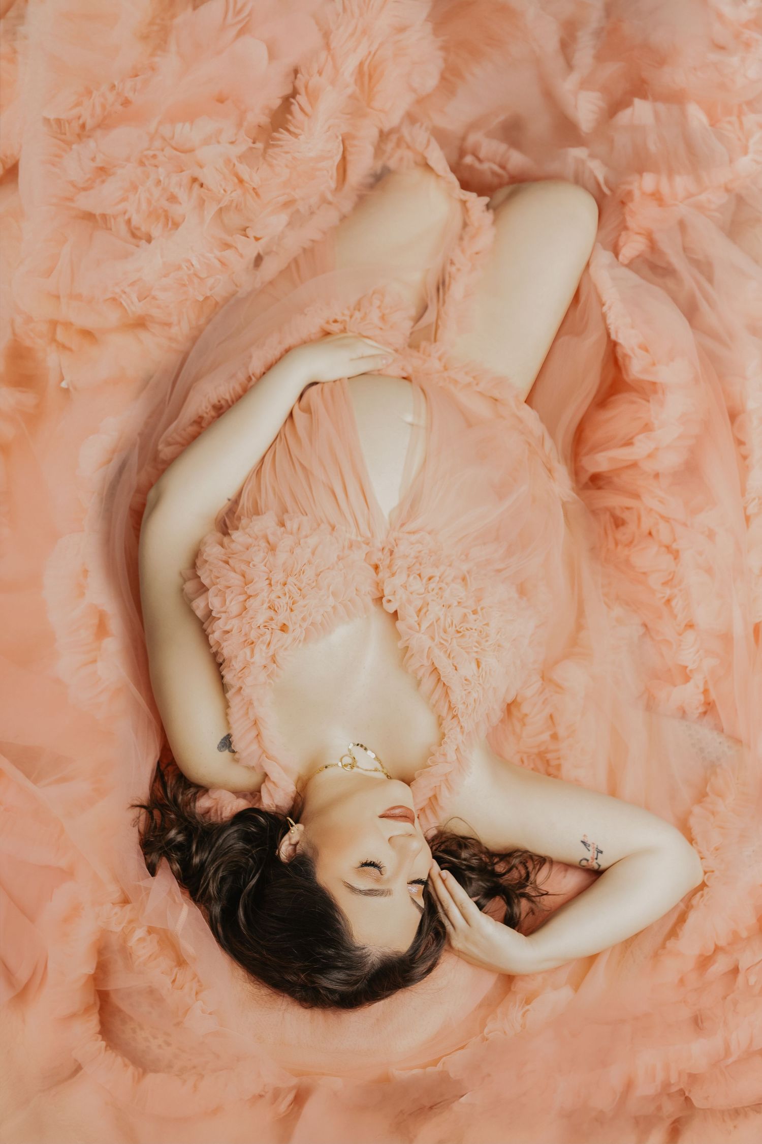 Artistic portrait series showing a figure lying on peach-colored tulle fabric in various dreamy poses.