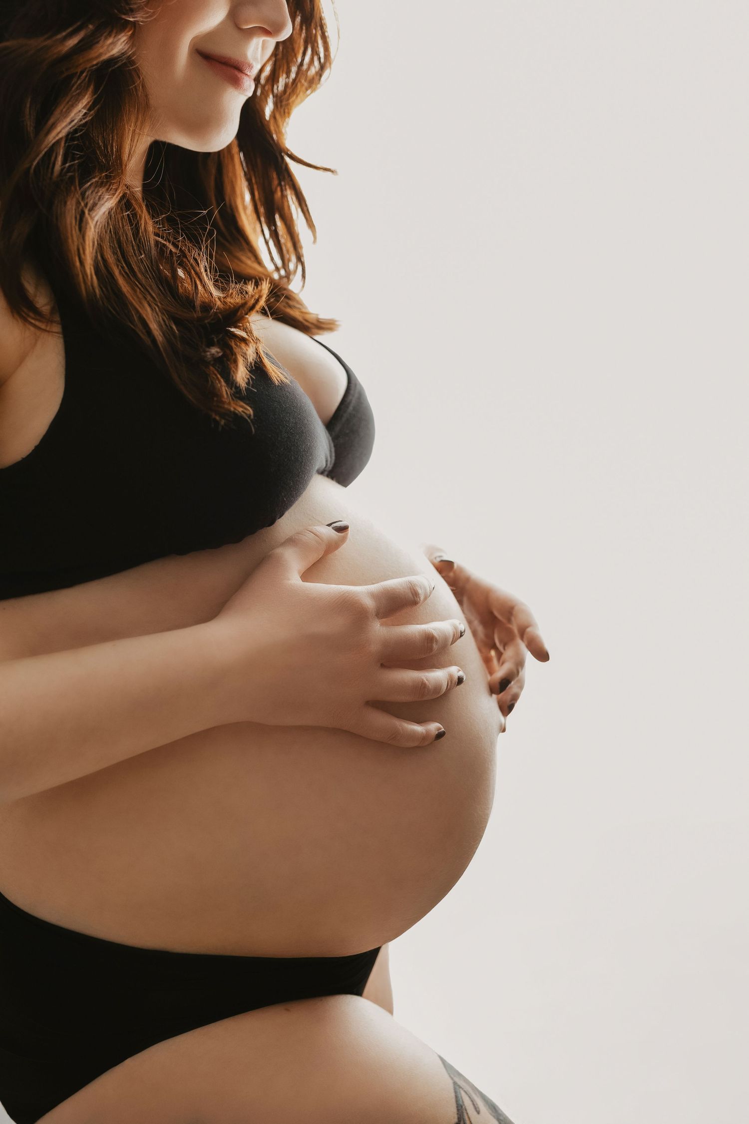 Minimalist black and white maternity photos showing belly silhouette against light background.