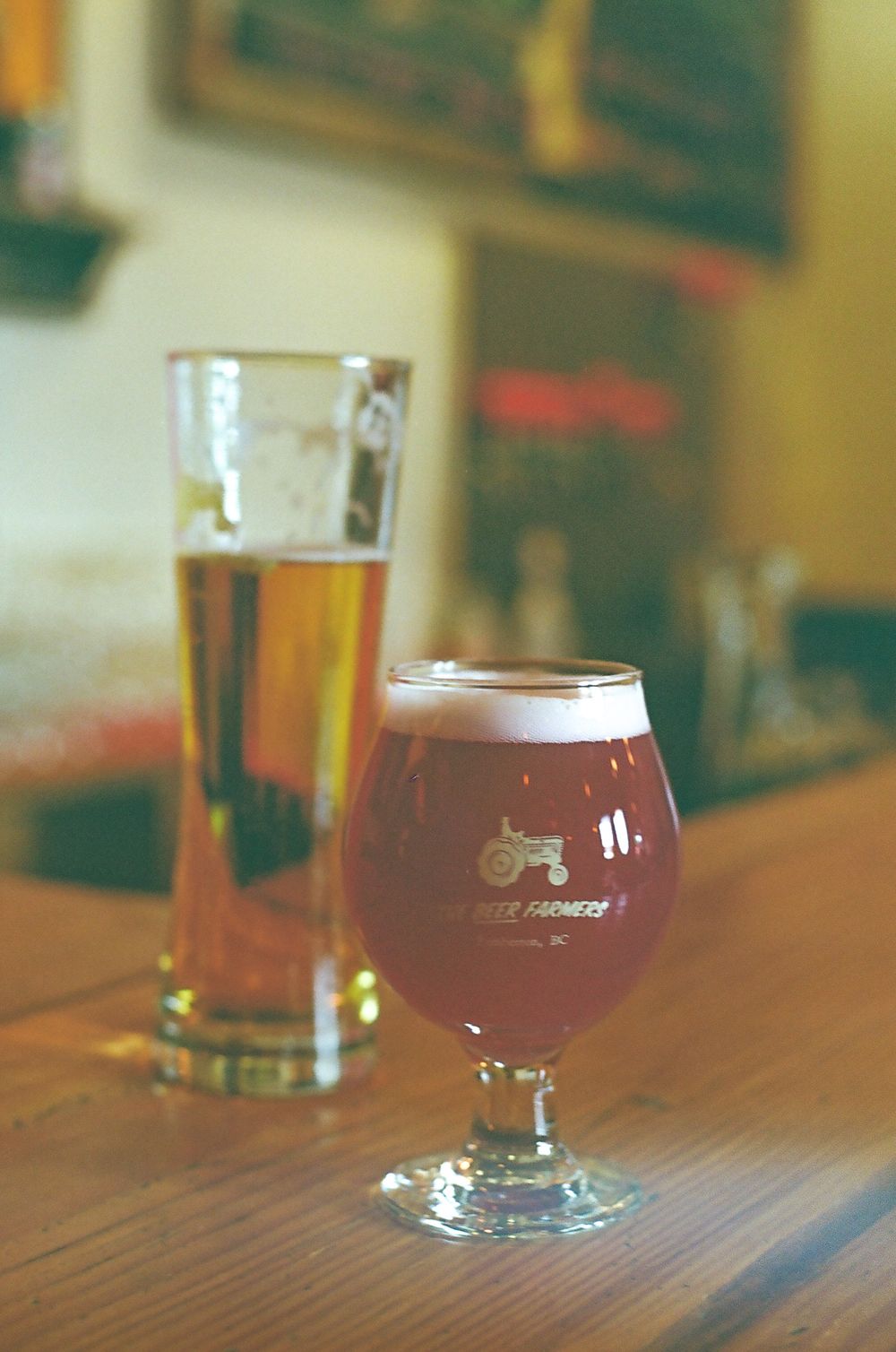 Row of craft beer glasses on wooden table in pub setting.