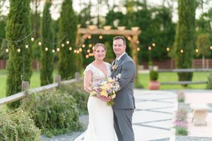 Wedding portrait in garden setting with string lights and cypress trees.