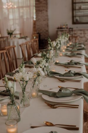 Elegant table setting with white linens, glass bud vases, and candlelight creating a romantic atmosphere.
