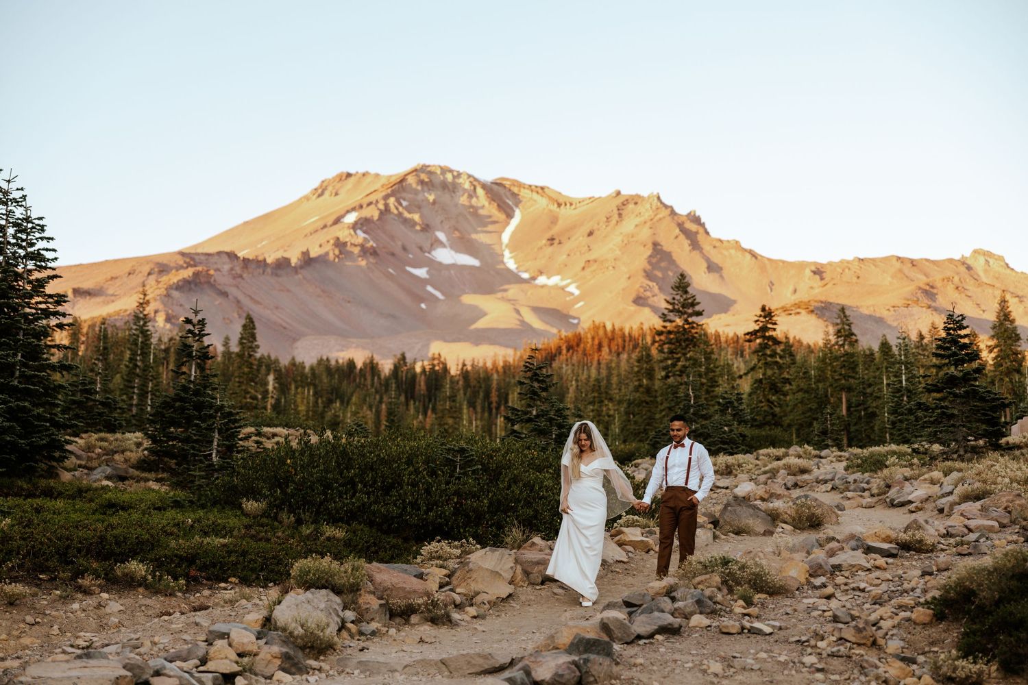 bride and groom walking down steps with Mount Shasta behind them during Mount Shasta Elopement day in Northern California - Bunny Flat Trail