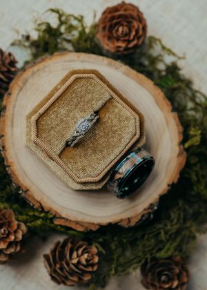 Fall themed wedding ring flat lay with gold, green, and brown tones.