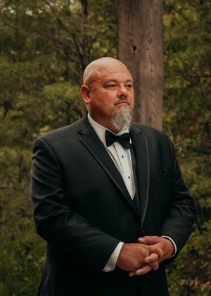 A groom stands with finger interlocking patiently waiting for his bride to walk down the aisle.