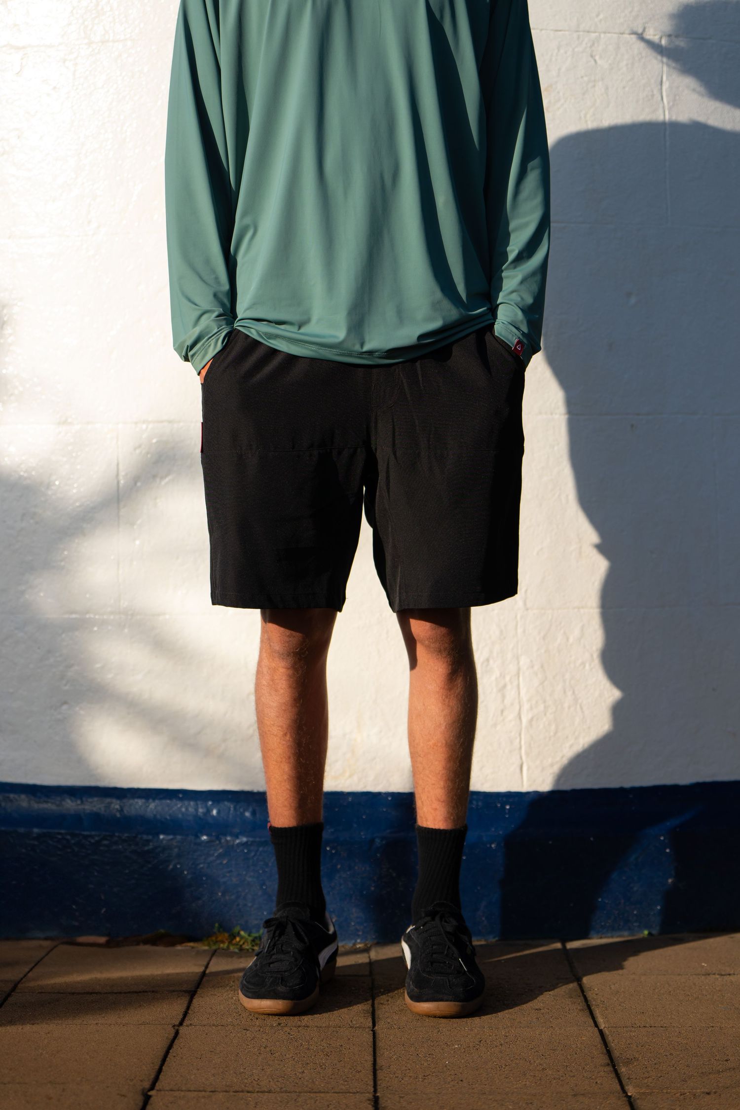 A series of cropped photos showing a person wearing green shirt and black shorts standing against a white wall.
