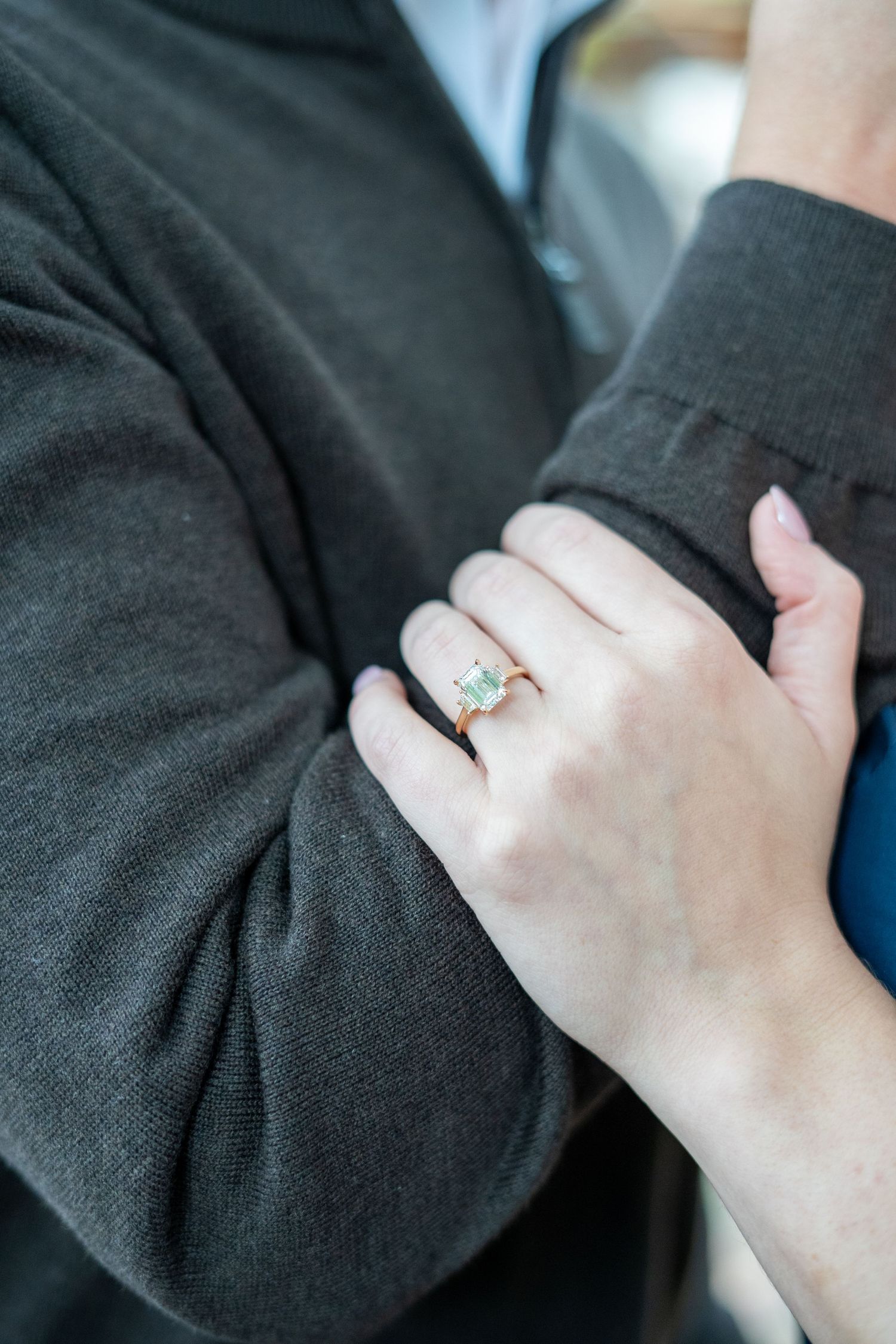 A close-up series of photos showing a hand wearing a delicate engagement ring with a light blue stone against black fabric.