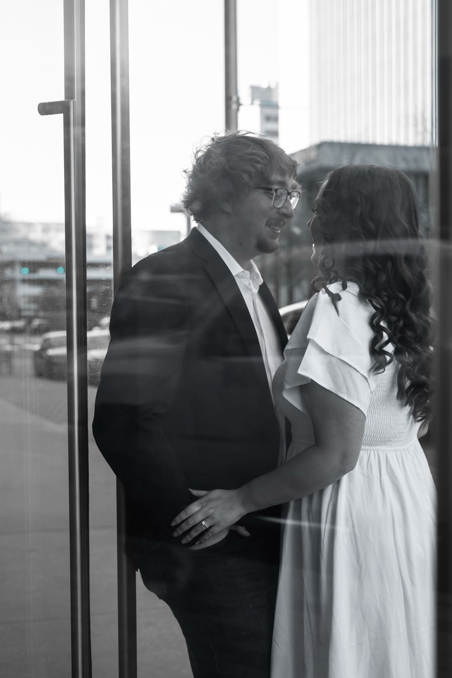 A romantic black and white photo sequence showing a couple in formal attire embracing near large windows.