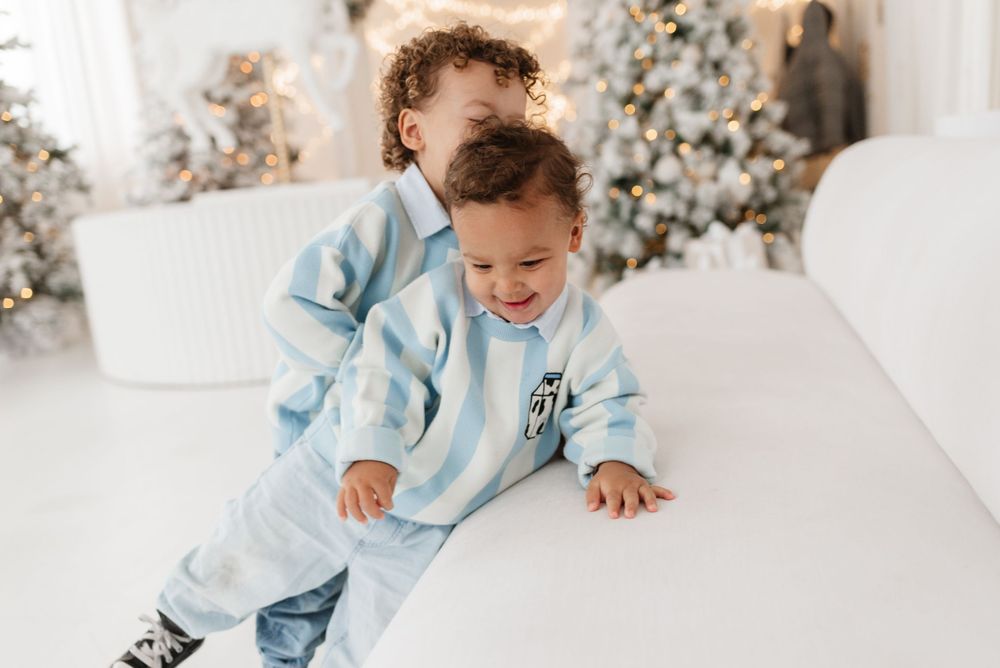 Siblings smiling and playing in a light and airy, Christmas setup at Toronto’s Mint Room Studio, captured by Jess GC Photography.
