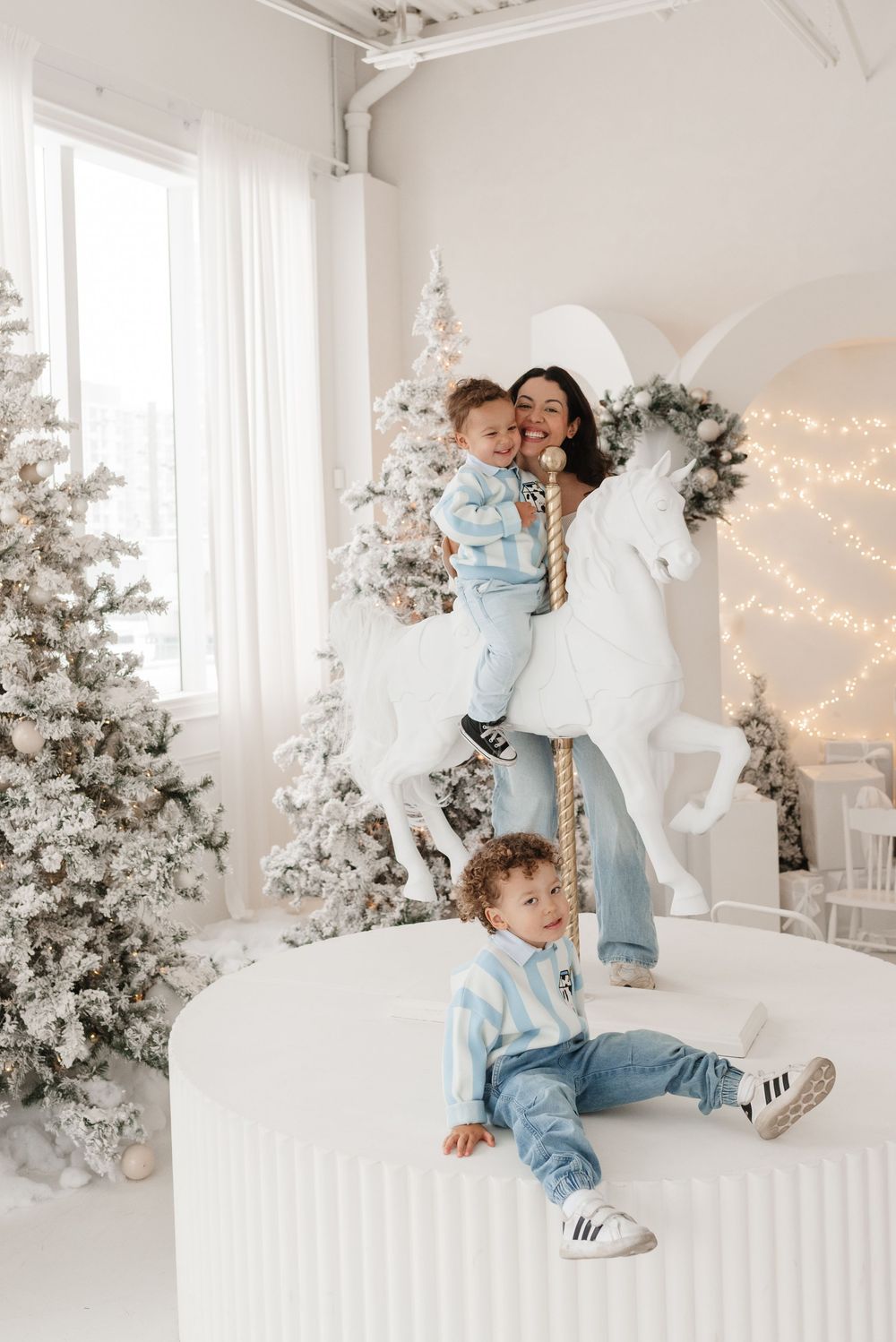 Family smiling and cuddling in a bright, elegant Christmas carousel setup at Toronto’s Mint Room Studio.
