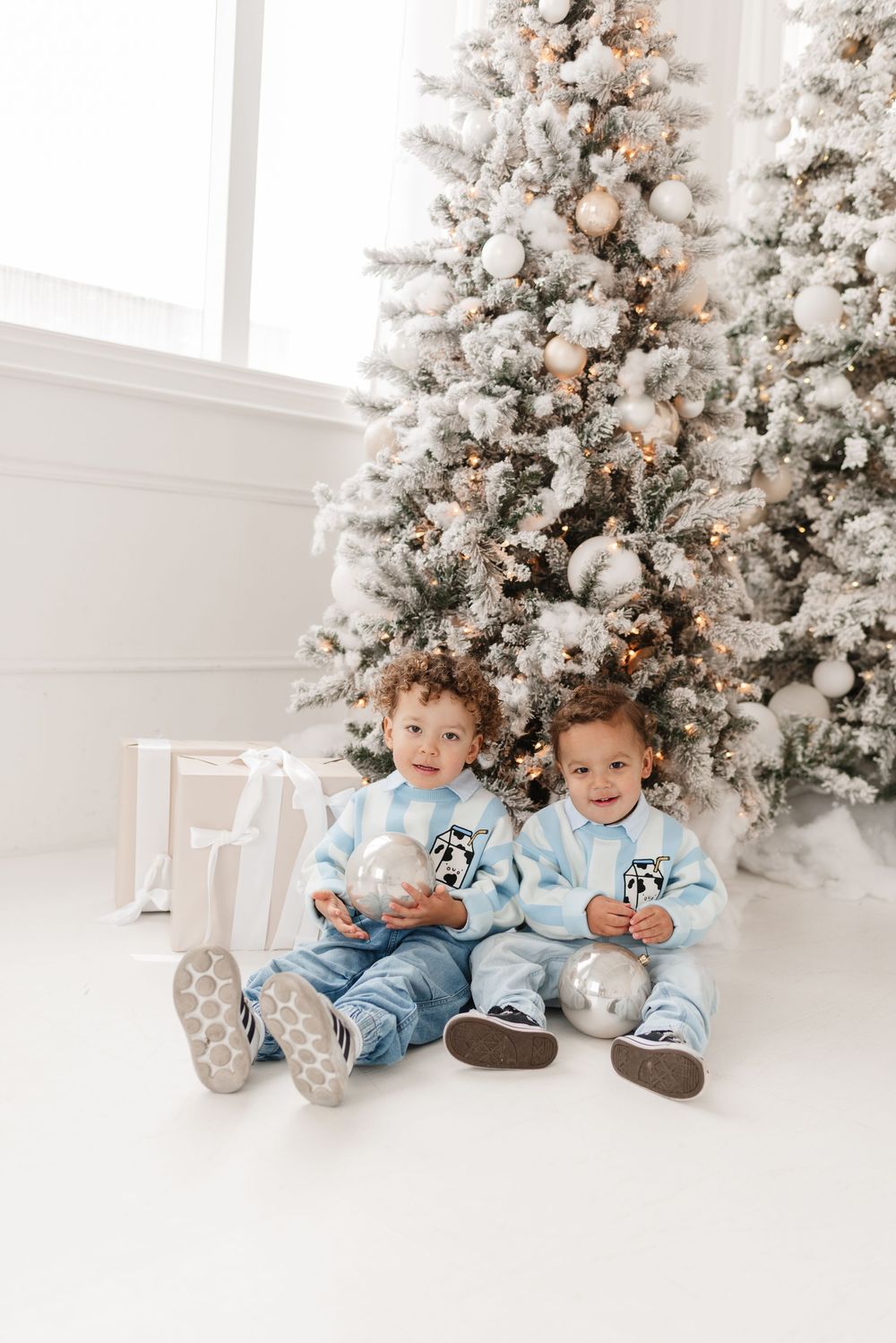 Siblings sharing a heart warming moment on a holiday-themed set with soft, warm Christmas lights for mini Christmas photoshoot in Toronto.