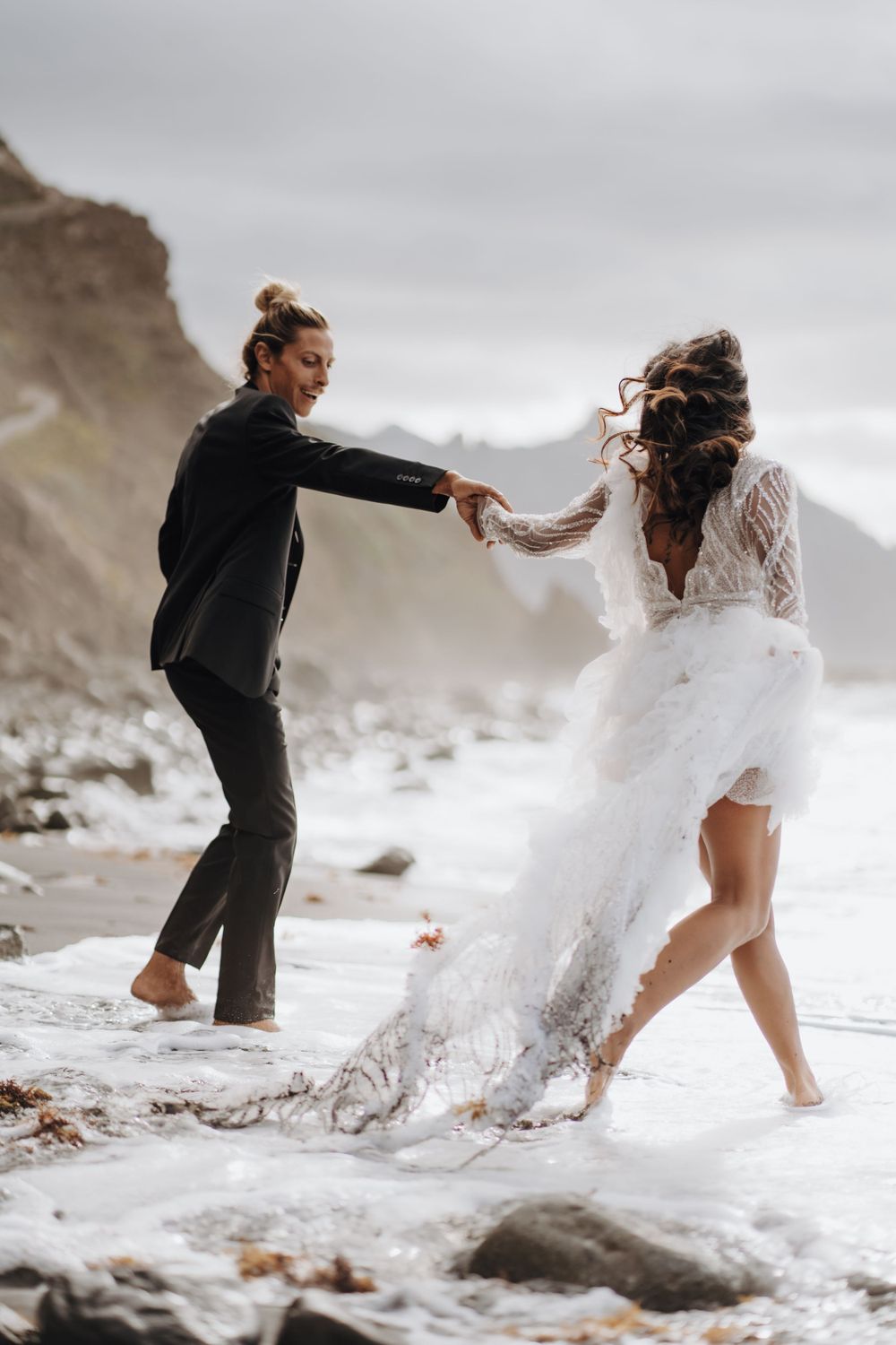 Dancing in the ocean waves during a dramatic beach photoshoot.