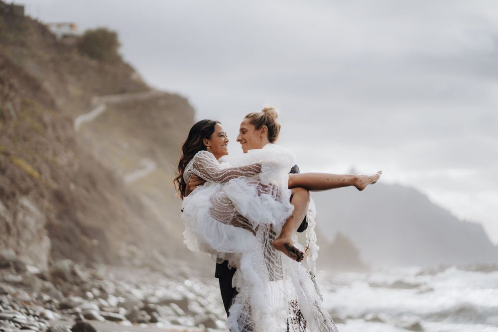 Romantic lift pose on a dramatic rocky beach with crashing waves.