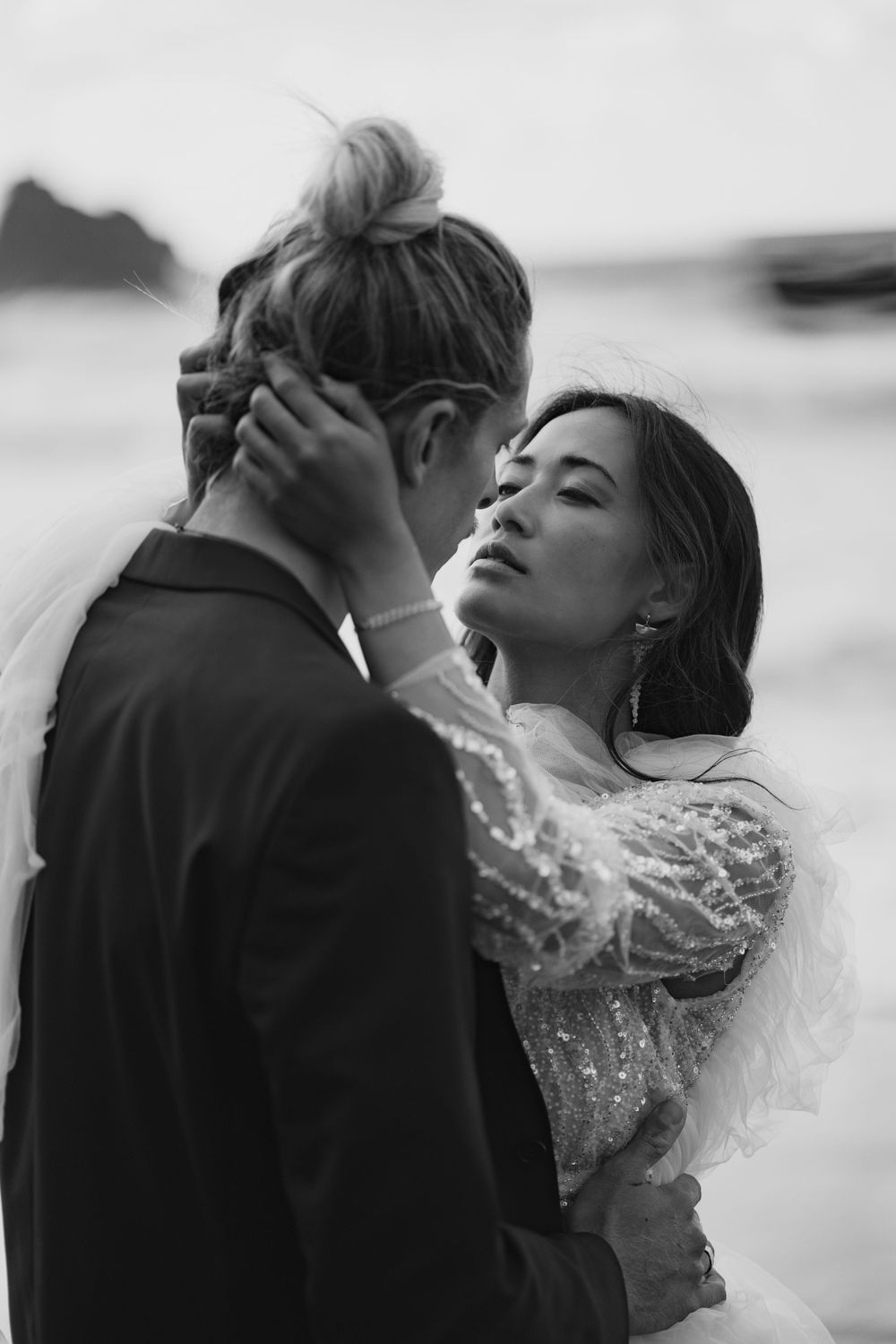 Intimate black and white portrait on misty oceanside cliff.