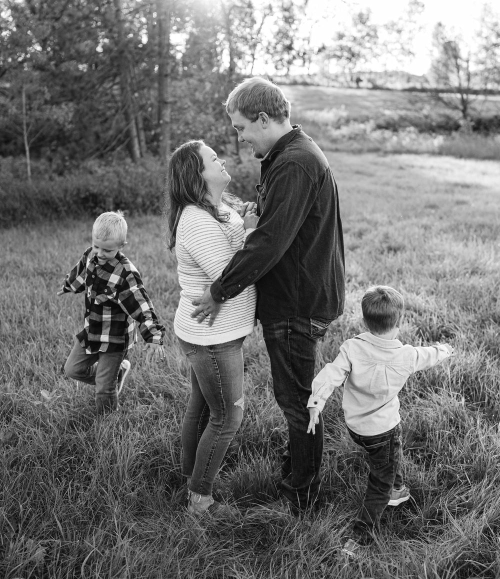 Black and white family portrait with two children playing in field.