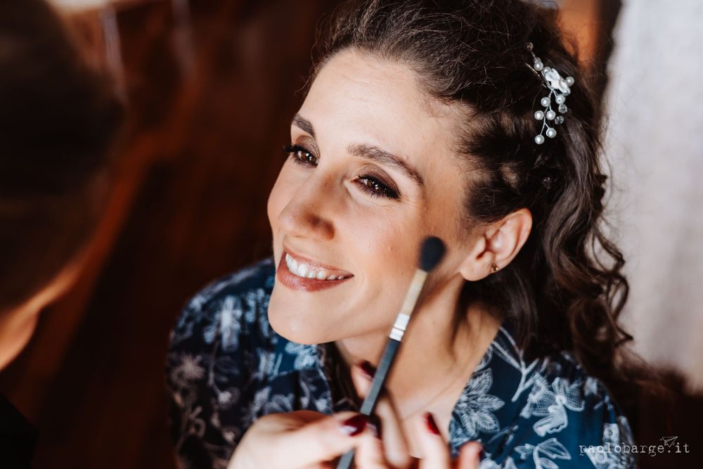 Getting ready moment with makeup application against blue floral background.