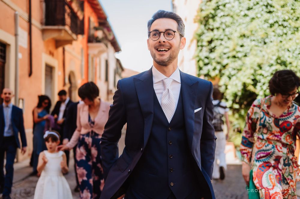 A person in a stylish navy suit walking on a charming Italian street.