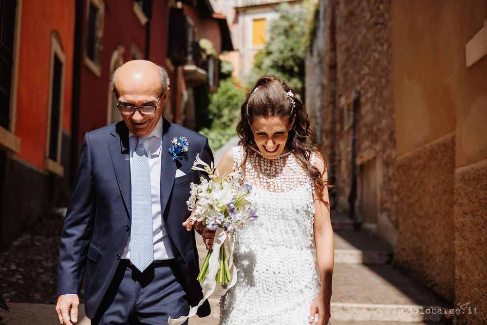 A couple walking through a narrow Italian alleyway with rustic orange walls.