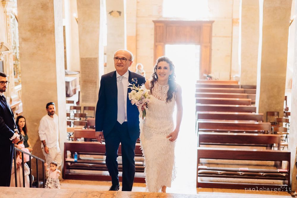 A couple walking down the aisle in a sunlit church with classic architecture.
