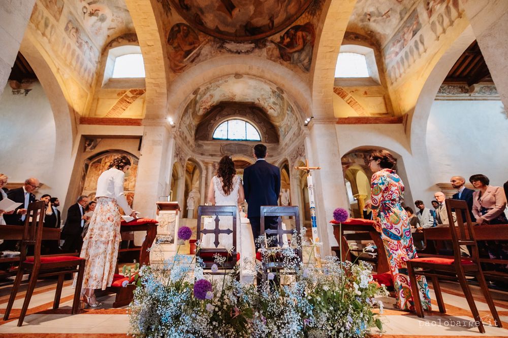 A wedding ceremony in a baroque church with painted ceilings and floral decorations.