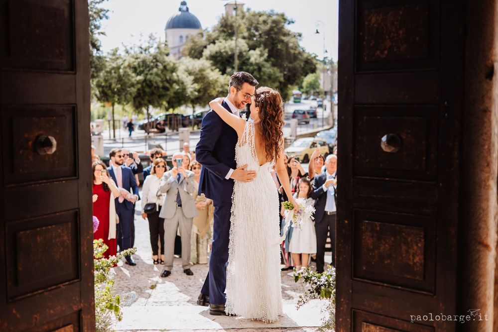 Wedding celebration outside a church with gathered guests watching the ceremony on a sunny day.