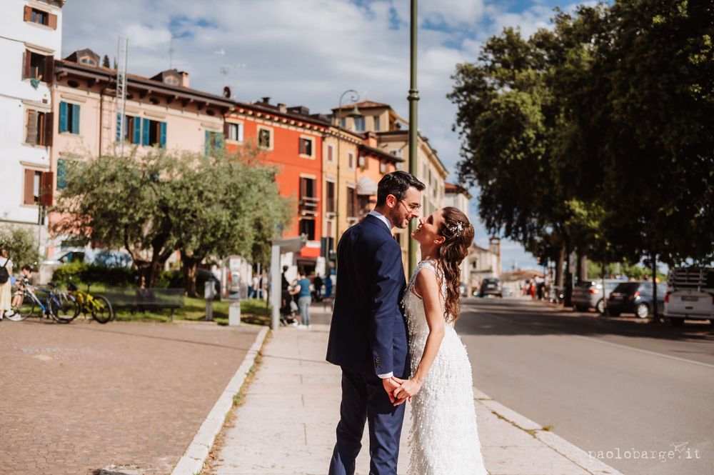 Newlyweds share a romantic moment on a charming Italian street with colorful buildings in the background.