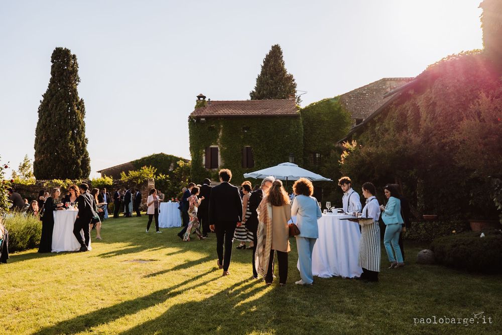 Outdoor wedding reception on a sunny lawn with guests gathering under white umbrellas.