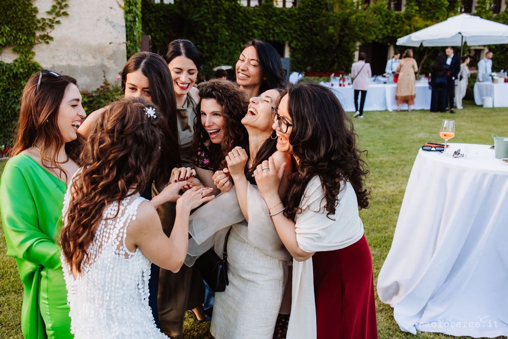 Group of wedding guests celebrating and laughing together during outdoor reception.