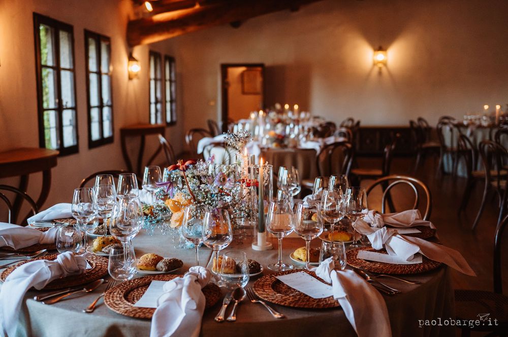 Elegant wedding reception table setting with glassware, candles and white linens in a rustic venue.