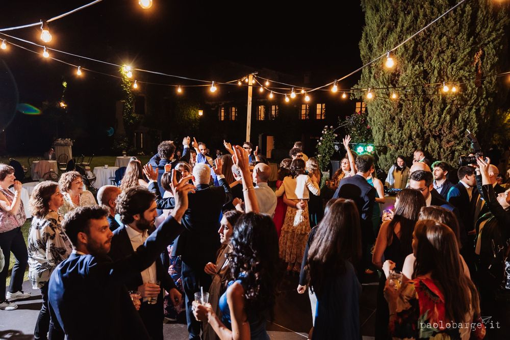 Lively dance party under string lights with guests celebrating at night.