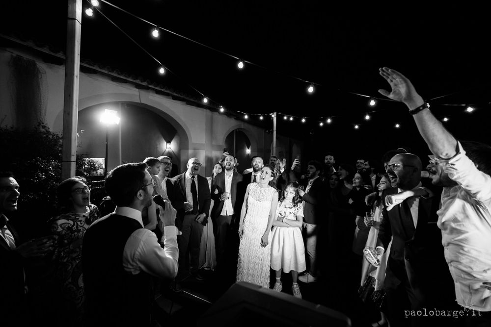Black and white photo of nighttime celebration with dancing under string lights.
