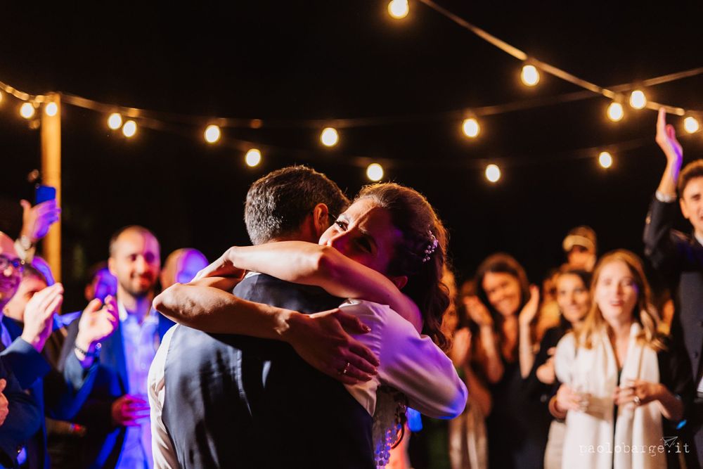 Couples dancing under romantic string lights at an outdoor wedding reception celebration.