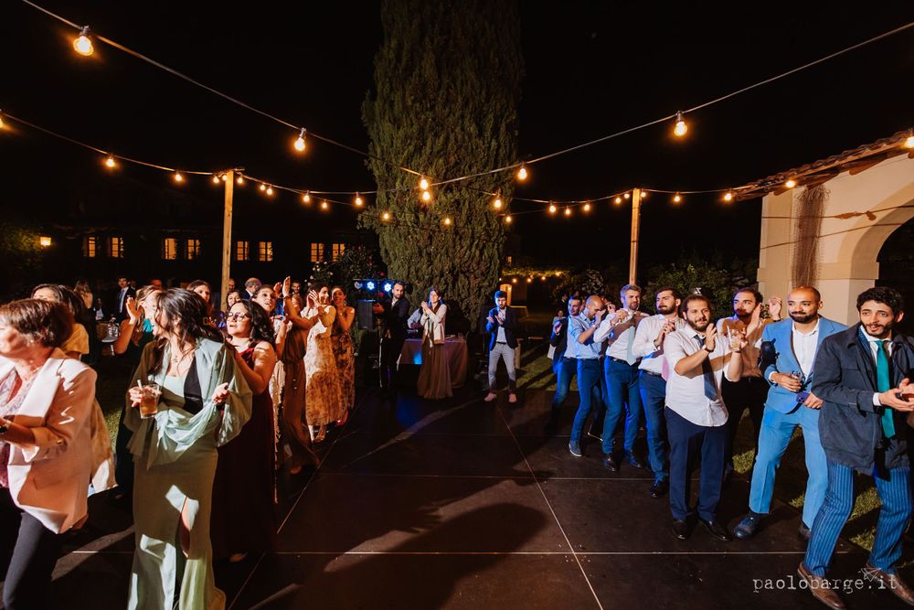 Wedding guests gathered outdoors under string lights during an evening celebration.