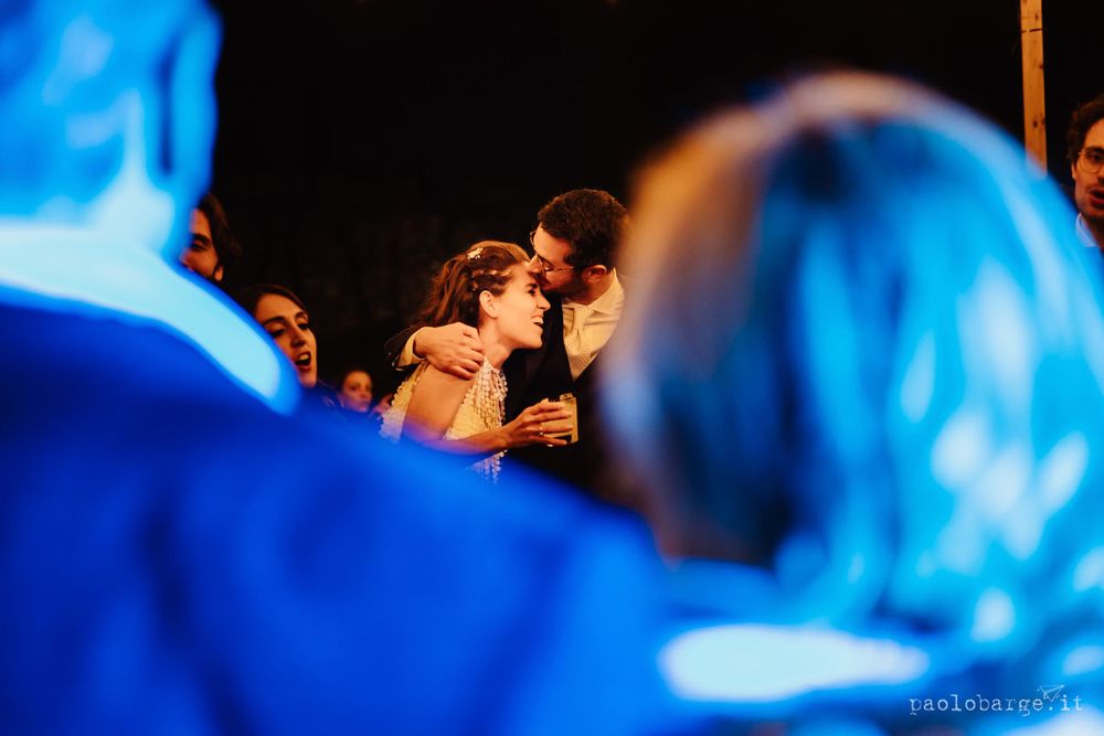 Intimate dance moment captured through crowd with blue lighting effects.