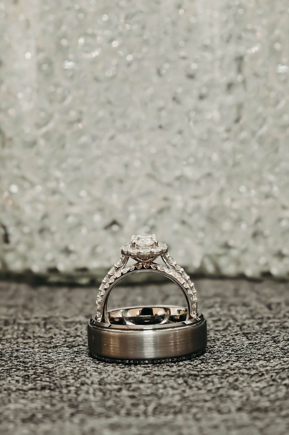 Wedding rings photographed on a textured surface showing a diamond engagement ring and matching band.