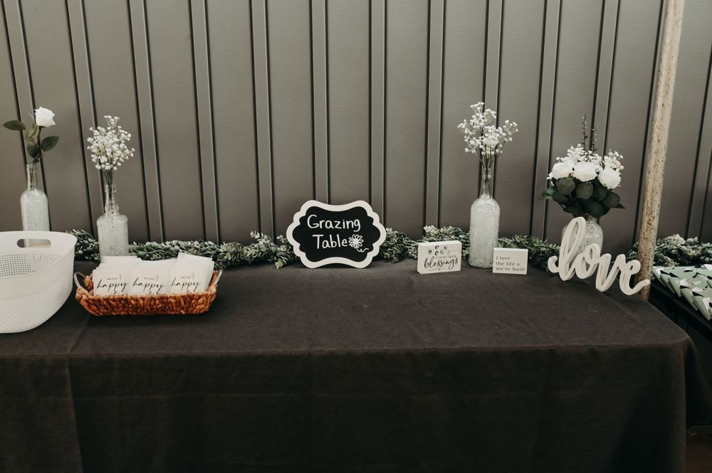 Wedding reception table with black tablecloth decorated with white flowers, candles and 'love' signage.