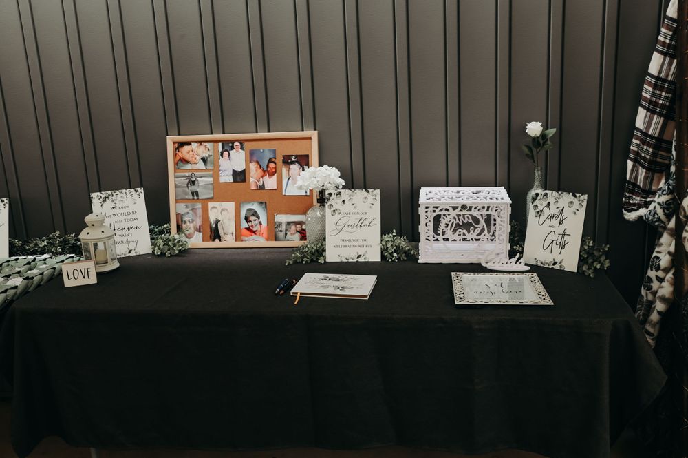 Wedding memory table with photo collage and decorative elements on black tablecloth.