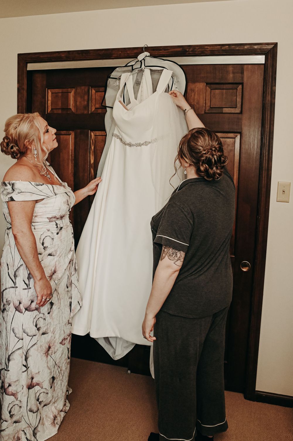 Wedding dress preparation scene with floral print bridesmaid dresses in an indoor setting.